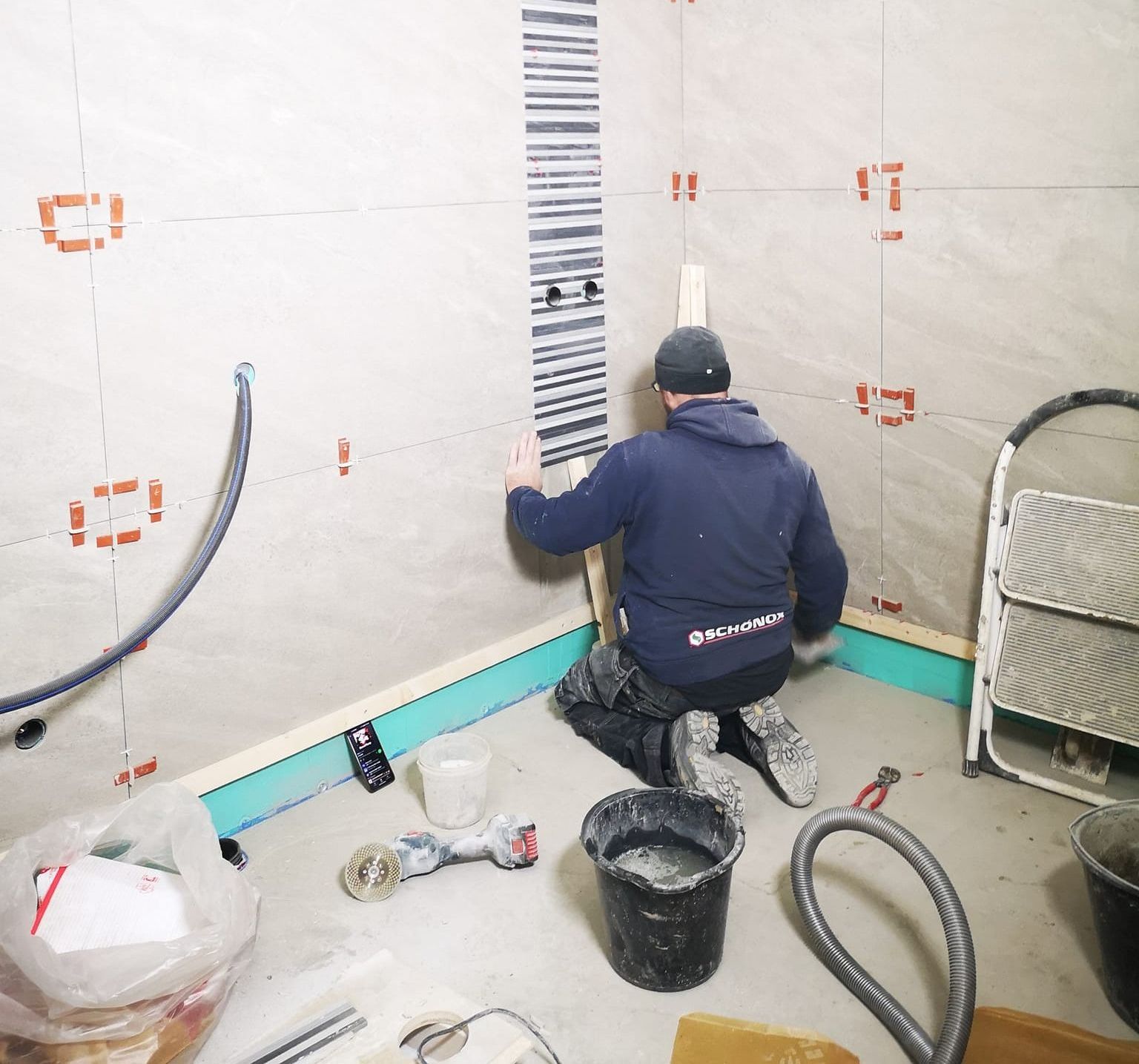 En ansatt som legger fliser på veggene